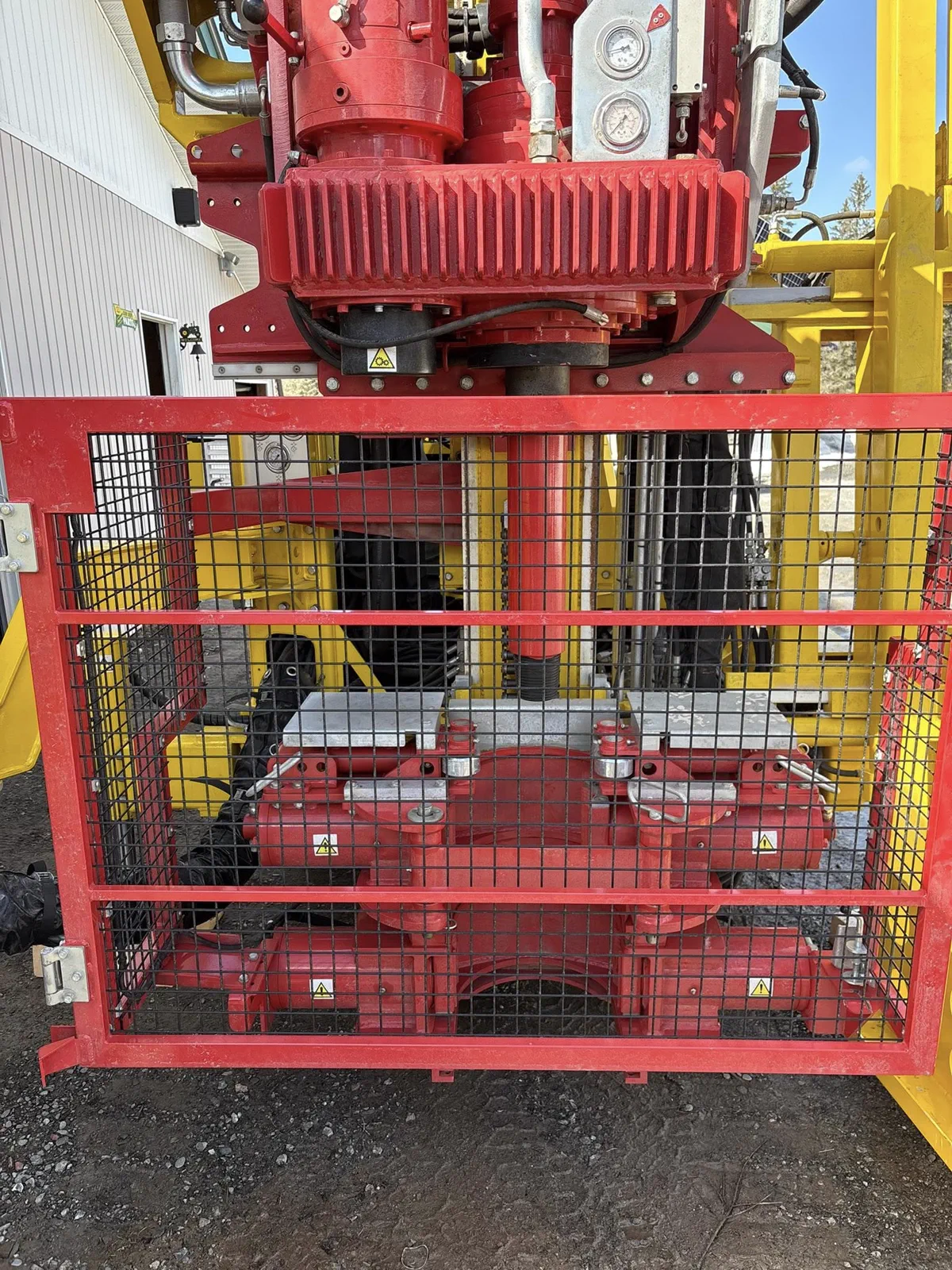 Close detail of red drill head components behind a protective guard.