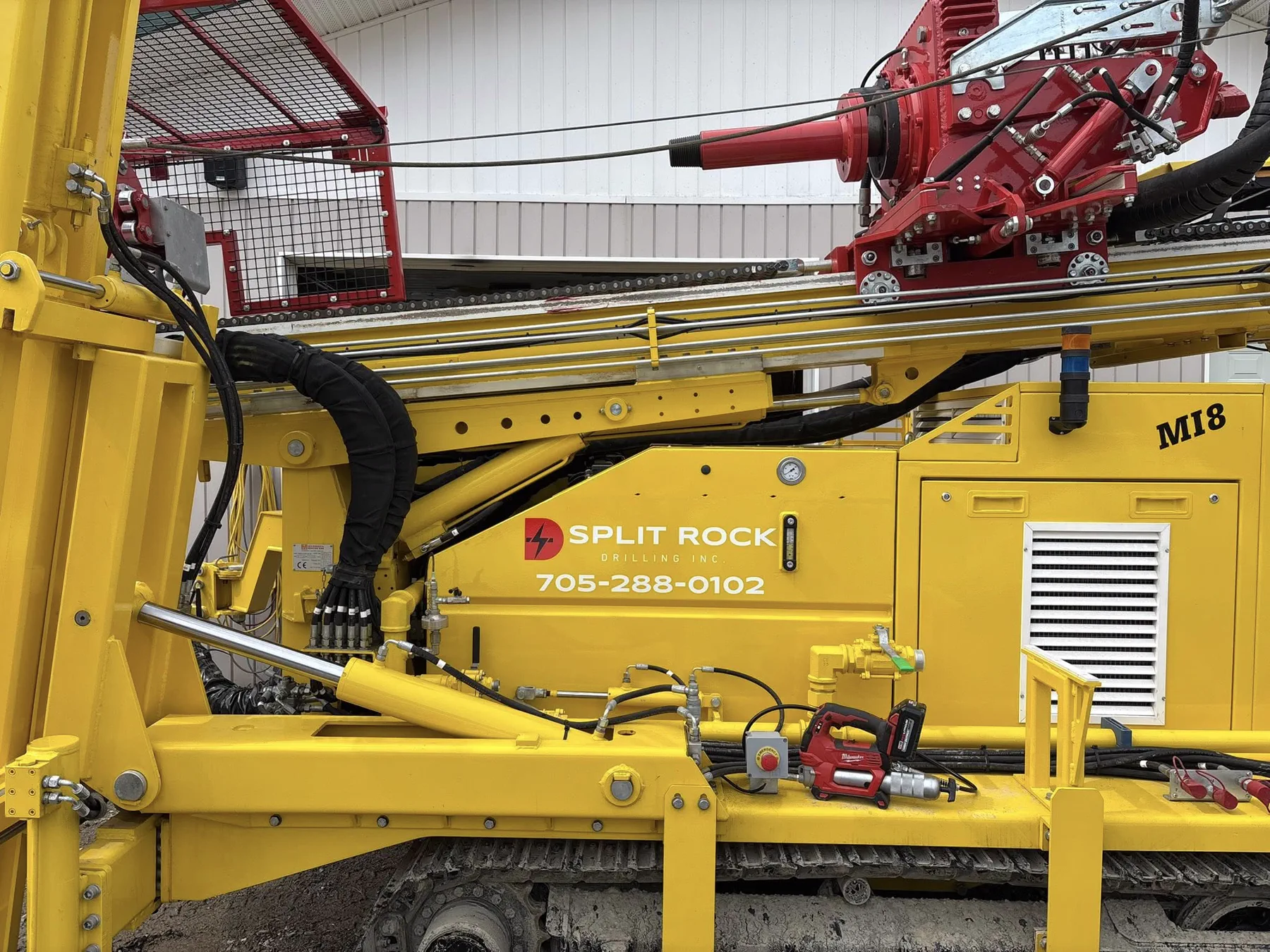 Close-up of the Split Rock Drilling tracked rig with company branding and phone number.